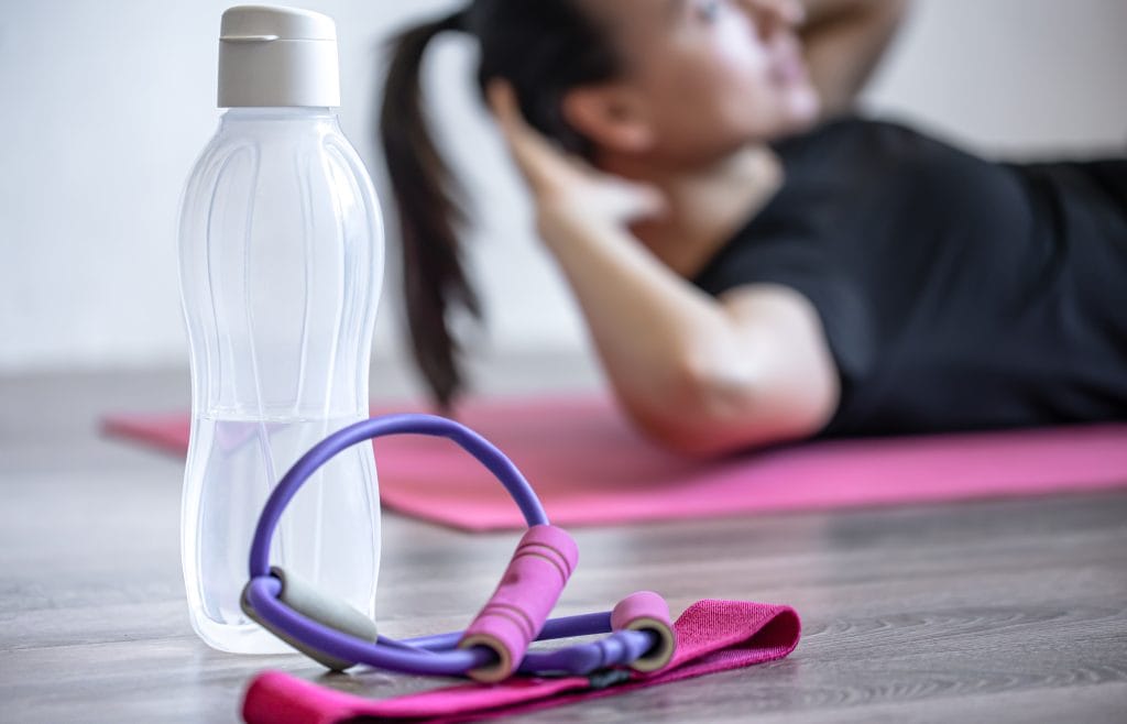 bottle of water and an elastic band for fitness on a blurred background. reprise sport post partum